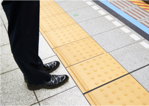 駅のホームで黄色い線の内側で待っている人